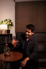 Businessman holding a glass of whiskey, sitting and drinking 