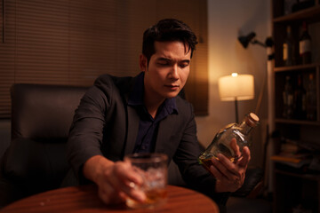 Businessman holding a glass of whiskey, sitting and drinking	