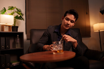 Businessman holding a glass of whiskey, sitting and drinking 