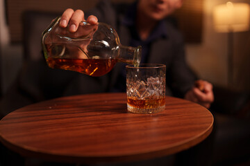 Businessman holding a glass of whiskey, sitting and drinking	