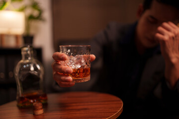 Businessman holding a glass of whiskey, sitting and drinking	