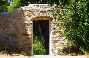 Ancient stone gate entrance in the forest with green trees