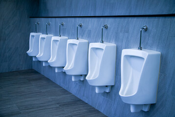 Interior of modern and classic restroom with white wall and warm light, Row of sanitary ware with men urinals in public toilet.