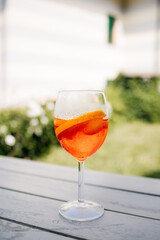 Refreshing spritz cocktail standing on wooden table in summer garden