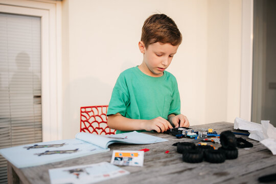 Young boy building a toy car following instructions at home
