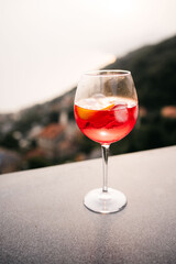 Red cocktail standing on a terrace overlooking a city at sunset
