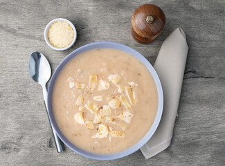 Onion soup with cheese in a bowl and seasonings over stone background