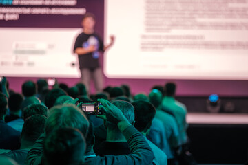 Professional conference featuring a speaker on stage engaging an audience in attendance.