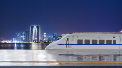 Modern high-speed train at night with city skyline in the background