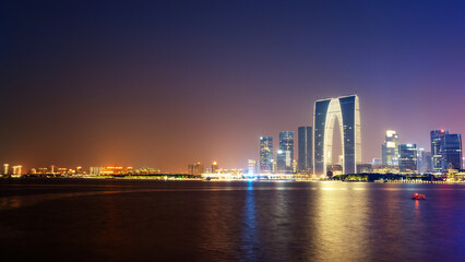 Night view of modern city skyline with illuminated skyscrapers by the water
