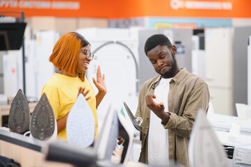 African american Couple standing in an electronics store choosing an electric iron for Ironing...