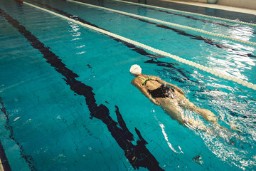 Woman swimming with swimming hat and swimsuit in swimming pool