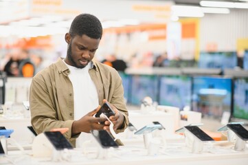 handsome young man buying new mobile in the electronic shop.