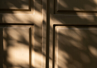 Sunlight casts intricate shadows on textured wall panels in a quiet outdoor setting during the late afternoon