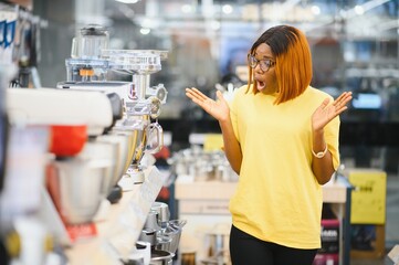 African american woman choosing kitchen mixer blender in home appliance shopping mall supermarket