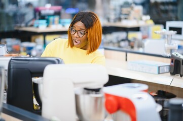 African american woman choosing kitchen mixer blender in home appliance shopping mall supermarket