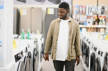 Household appliances store. An African American man buys a new modern washing machine