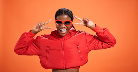 Sunglasses, excited and black woman with peace sign for fashion, style or trendy. Happy African model, studio or v hand gesture for victory symbol, emoji or cool influencer laugh on orange background