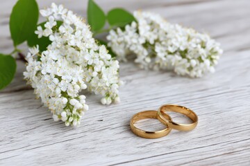 Golden wedding rings with white flowers on rustic wood for elegant romantic decor