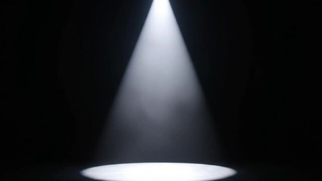 A single white spotlight shines in a dark space illuminating a circular area on the floor