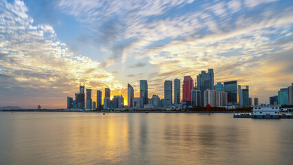 Fototapeta premium Beautiful sunset view of modern city skyline by the water