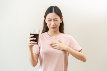Acid reflux disease, suffer asian young woman, girl hand holding a glass of cola, have symptom...