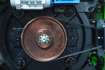 Close-up of a machine with a brown gear as part of a large industrial mechanism, belt transmission....