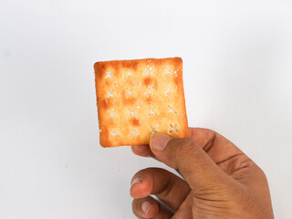 isolated hand holding a square sweet cracker with sprinkled sugar on top on a white background