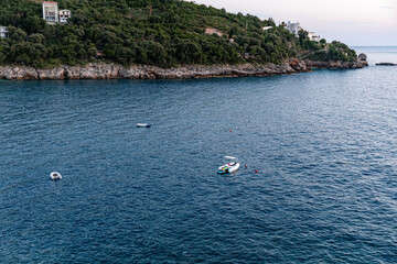 Small boats floating in a quiet bay near a forested cliff on the Montenegrin coast. Ideal for...