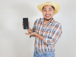 Asian male farmer wearing a rattan hat while showing the screen of the smartphone he is holding