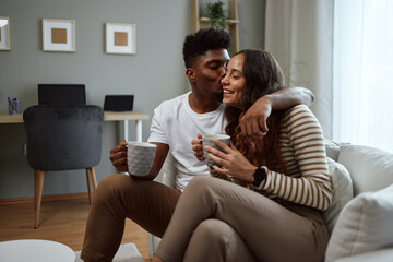 Obraz premium Happy couple sharing a loving moment while drinking coffee on sofa at home