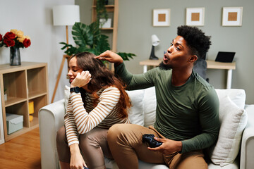 Boyfriend distracting girlfriend while playing videogames at home