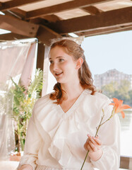 A girl in a white airy suit in a gazebo against the backdrop of a river.