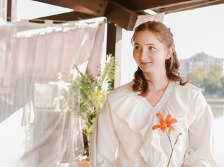 A girl in a white airy suit in a gazebo against the backdrop of a river.