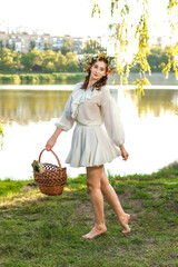 A girl in a wreath of flowers with a basket on Ivan Kupala Day.