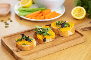 Healthy autumn snack with pumpkin spread and seed topping on wooden board. Pumpkin hummus