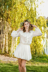 Girl in a wreath against the background of a river at sunset.