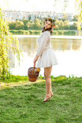 A girl in a wreath of flowers with a basket on Ivan Kupala Day.