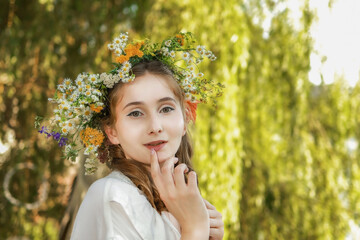 Girl in a wreath against the background of a river at sunset.