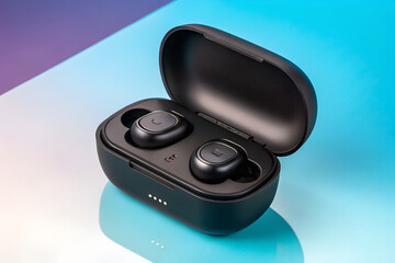 Modern black wireless earbuds with charging case open resting on a reflective surface with a gradient background of purple and blue colors