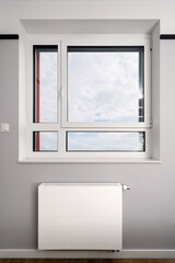 Modern electric heater under a large window in a contemporary apartment
