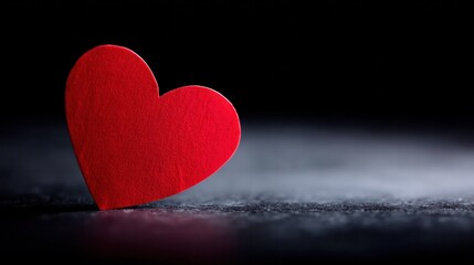 Fototapeta premium Glossy red heart centered on clean black backdrop, highlighting warmth and symbolic affection