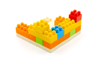 Colorful plastic building blocks assembled into a structure on white background