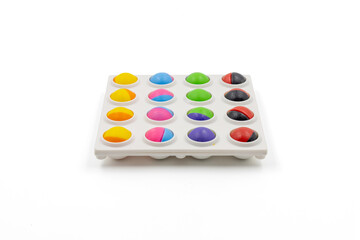 Colorful half-sphere shaped toy balls arranged on a white tray over white background