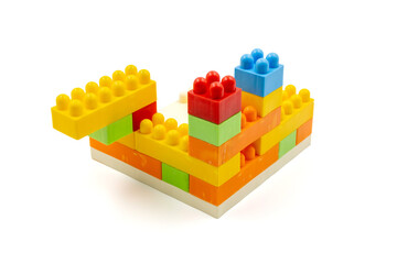 Colorful plastic building blocks assembled into a structure on white background