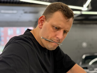 A car wrapping specialist applies a polyurethane film to the car. Detailer smoothes PPF. Car...