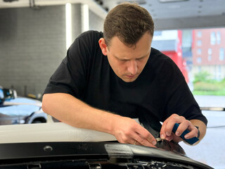 A car wrapping specialist applies a polyurethane film to the car. Detailer smoothes PPF. Car...