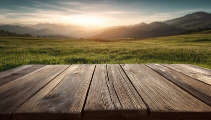 Serene wooden table in open grassy meadow with mountain sunset backdrop, warm sunlight glow for product display branding and outdoor promotional concepts. 