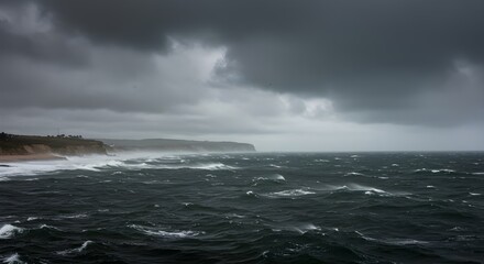 Cloudy coastal scene with grey skies, strong wind, and rough sea, concept of dramatic atmosphere, natural power, and intense weather conditions.