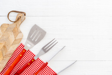 Set with barbecue utensils and equipment with red picnic napkin. Stainless steel tools. Top view